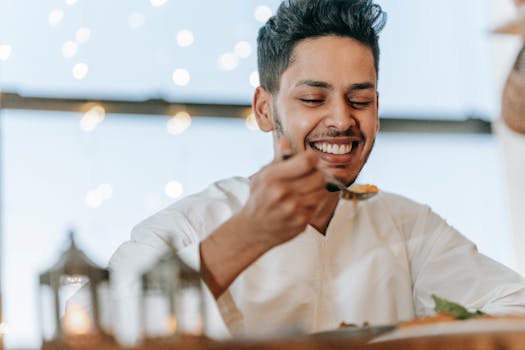 A smiling man enjoys a meal indoors, celebrating Ramadan with blissful expression.