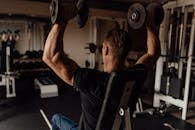 Adult man exercising with dumbbells in a gym, focused on fitness training.